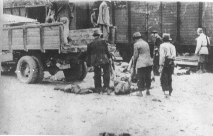 Under the supervision of Romanian guards, Gypsies load the corpses of victims of the Iasi-Calarasi death onto trucks in Targu-Frumos